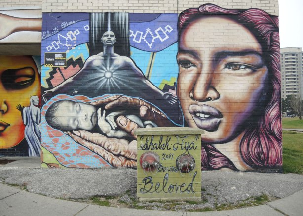 part of a mural by Shalak and Fiya Bruxa, a young woman holding a new born baby in her hand.