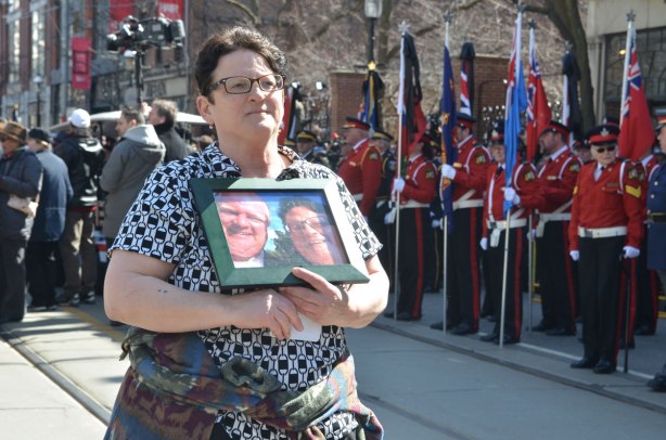 a woman holds a framed photo of a selfie of her and Rob Ford