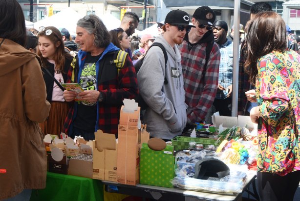 People at Yonge Dundas Square in Toronto celebrating 420 day - a group of people checking a vendor's wares. 