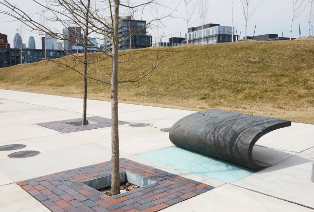 A curved black metal bench on a sidewalk