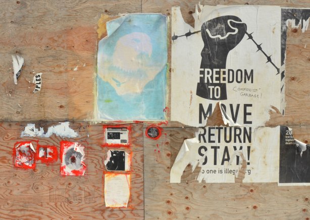 posters that have been on wood hoardings for quite a while and they are starting to fray at the edges. 