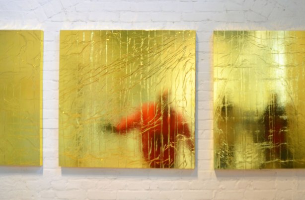 three square panels of reflective gold, wrinkled, material with reflections of people in them. 