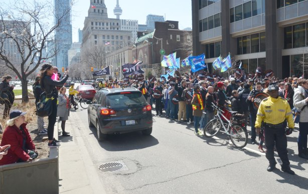 cars driving past the protest on University Ave., people lined up on the boulevard taking pictures of the rally