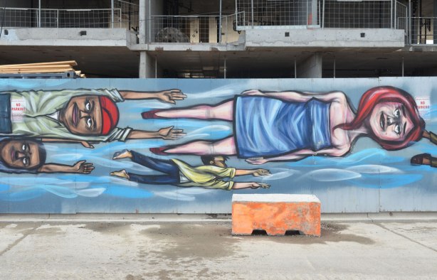 people flying sideways on a mural by elicser, including a woman in a blue dress and a man with a red hat. 