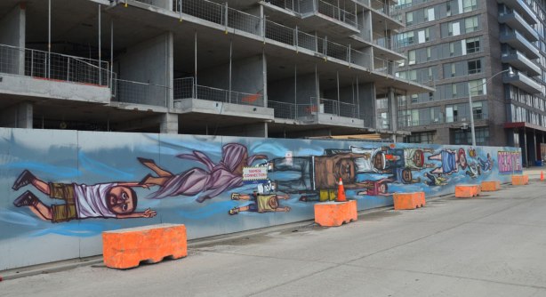 a long mural by elicser painted on hoardings around a building under construction. People flying past in the mural