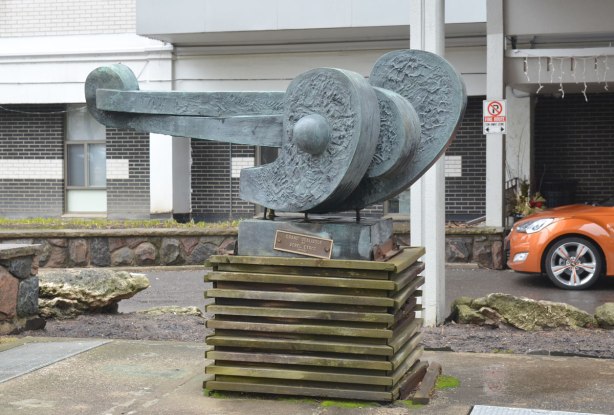 Grand Odalisque, a sculpture by Sorel Etrog sits on a wood pedestal in front of the entrance to an apartment building. 