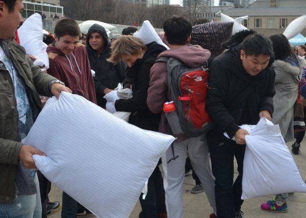people in the midst of a large pillow fight at Nathan Phillips square in celebration of international pillow fight day - 
