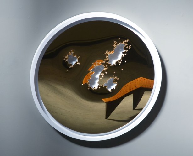 an artwork by Brendan McNaughton of a slightly concave mirror but with a few torn holes in it. A bench is reflected in the mirror but because the mirror isnt't flat, the bench is distorted. 