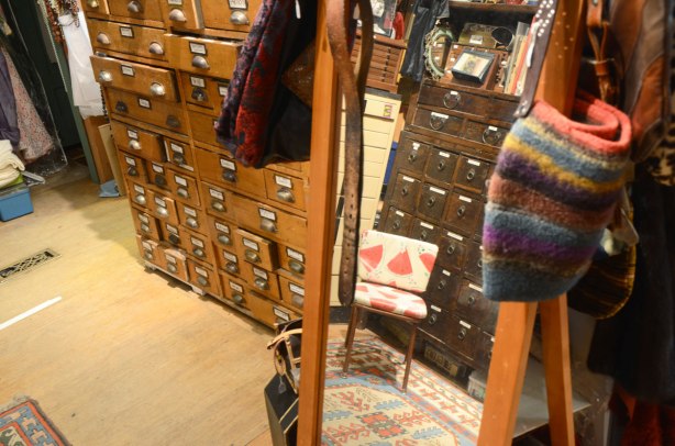old wooden drawers filled with old photographs, a mirror, and an old chair with a vinyl watermelon print fabric on it.