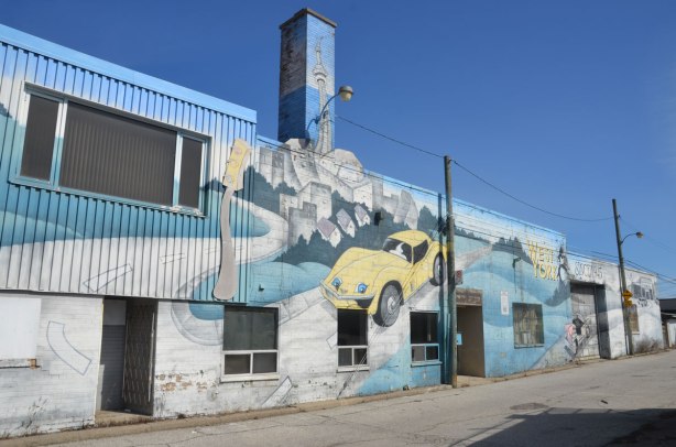 mural on the side of West York motors on St. Clair West - looking down the length of the mural including the narrow chimney on which the CN TOwer is painted. 