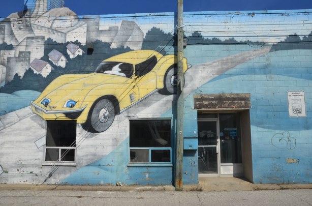 mural on the side of West York motors on St. Clair West - a yellow sports car is painted on the wall near the entrance to the building