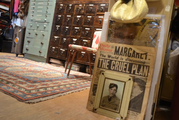 old photograph of a man in uniform, a front page of the Daily Mirror newspaper, more drawers, all in a store filled with vintage items.