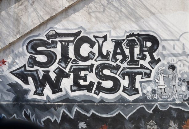 mural in black, white, and grey about the first railway in Ontario, 1853, that was built here, and where the railway still runs as the GO line to Aurora - the words St. Clair West in large letters