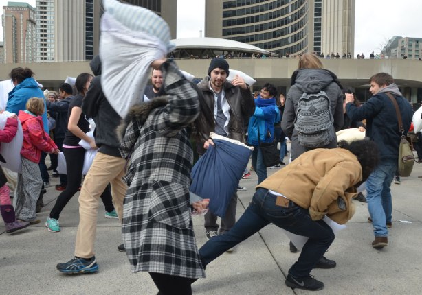 people in the midst of a large pillow fight at Nathan Phillips square in celebration of international pillow fight day - 