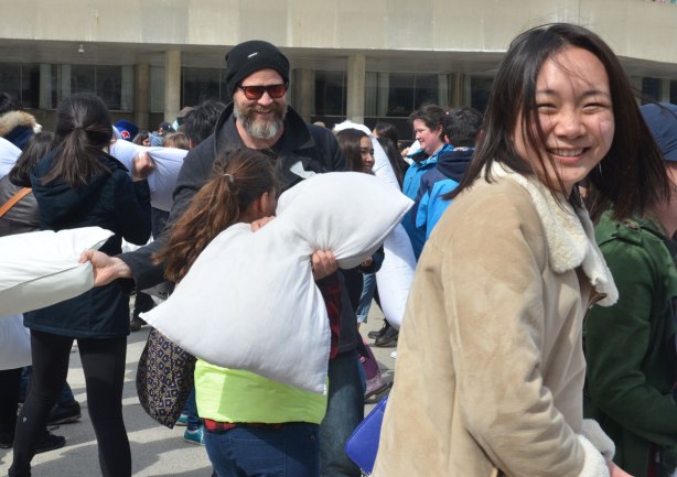 people in the midst of a large pillow fight at Nathan Phillips square in celebration of international pillow fight day - 