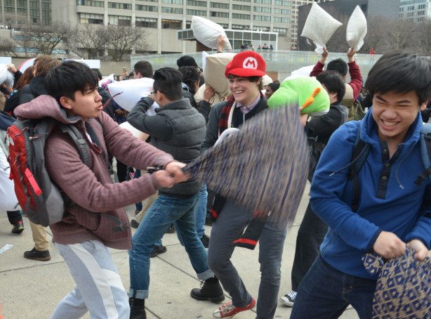 people in the midst of a large pillow fight at Nathan Phillips square in celebration of international pillow fight day - 