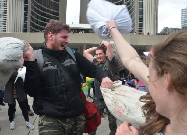 people in the midst of a large pillow fight at Nathan Phillips square in celebration of international pillow fight day - 