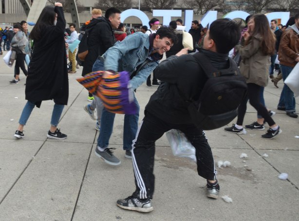 young men swinging pillows at each other in a large pillow fight