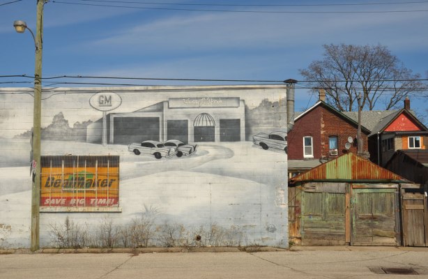 mural on the side of West York motors on St. Clair West near Osler - south end of the mural showing cars parked in front of a garagethe backs of two houses are also in the picture, 