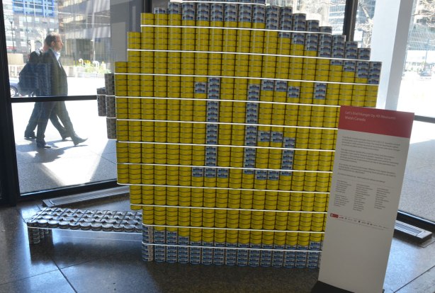 a large measuring tape (round and yellow) made of tin cans full of food to be donated. 