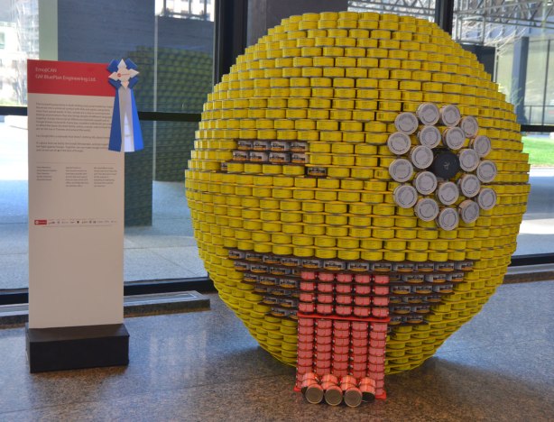 made of canned food, a large yellow circle meant to look like an emoji, winking with it's tongue out. It's about 5 feet high. 