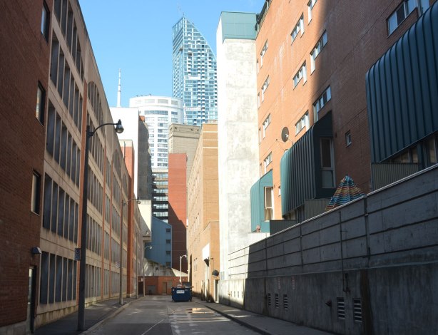 a downtown Toronto lane, very clean, no graffiti, taller, newer buildings on either side of the lane. CN tower in the distance, 