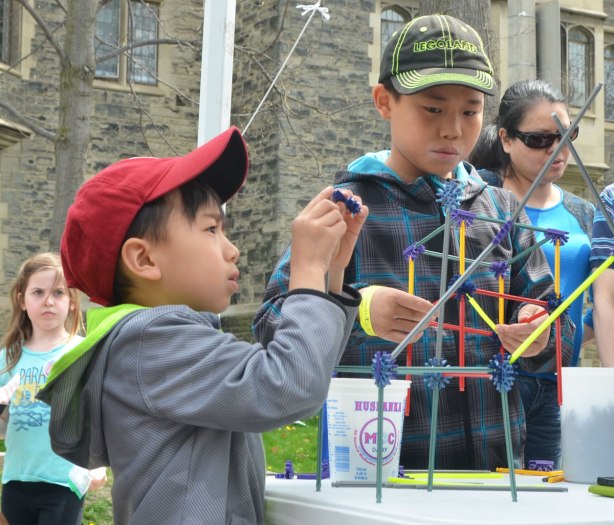 Two young Asian boys are building small structures with the building toy k'nex.