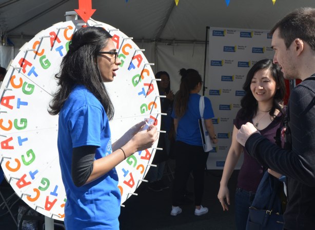 A young woman is standing beside a spinner with AT and GC being the possible landing places. She is talking to a couple who have spun and landed on GC