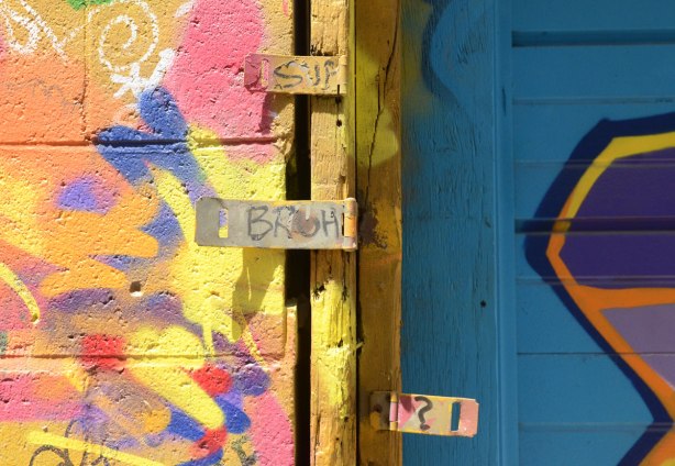 Three hinges have been bent forward so they are flat, multicoloured graffiti behind them, words written on the hinges except for the bottom one which has a question mark on it. 