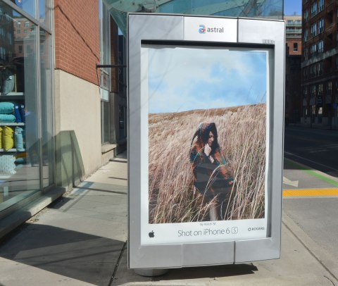 iphone ad on a bus stop wall showing a woman in a field