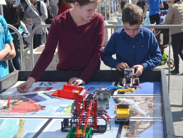 Two kids are playing with a programmable Lego car. 