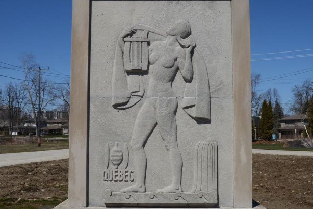 Quebec sculpture - A stone relief sculpture from a series on provinces of Canada, originally on a Bank of Montreal building in Toronto. They were rescued when the bank was demolished and moved to the grounds of the Guild Inn in Scarborough. By Canadian artist Frances Loring. A naked woman upright, with a cloth over her shoulders and looking upwards