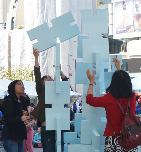 competition to build the highest, strongest tower out of hard styrofoam blocks, children and adults working together.