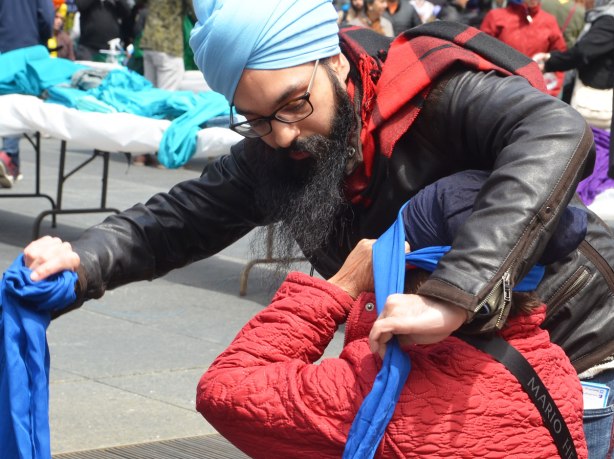 a man is wrapping a seated woman's head with a blue turban
