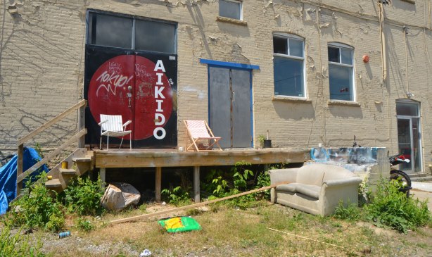 back deck of a light industrial building, no railing, two canvas chairs, steps down to ground level where there is a couch