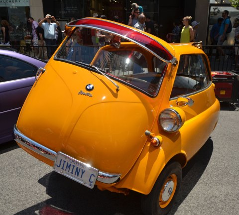 a yellow 1959 BMW Isetta 300 with its front door open - the front of the car opens up, parked on Bloor street for the Yorkville exotic car show. 