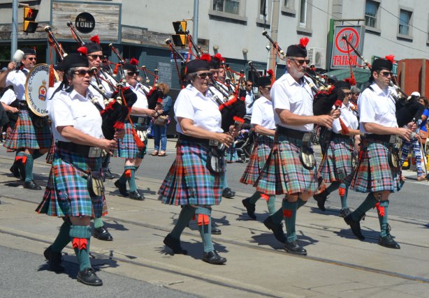 members of the Cobourg Legion pipe and drum band, four bagpipers in their blue and red kilts marching in a parade