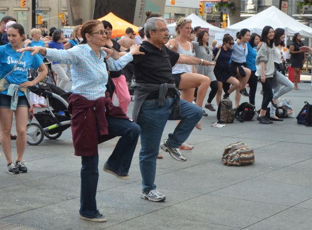 people dancing at Yonge Dundas Square as a group, part of an event called Sharing Dance - a middle aged couple