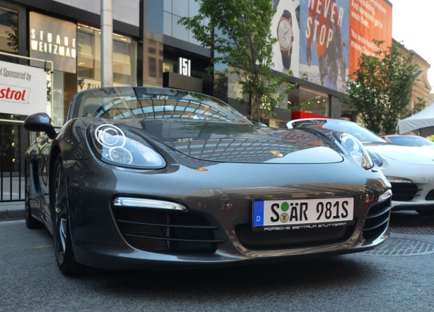 A dark grey Porsche with German licence plates is parked on Bloor Street, beside an older white Porsche, for the 6th annual Yorkville exotic car show. 