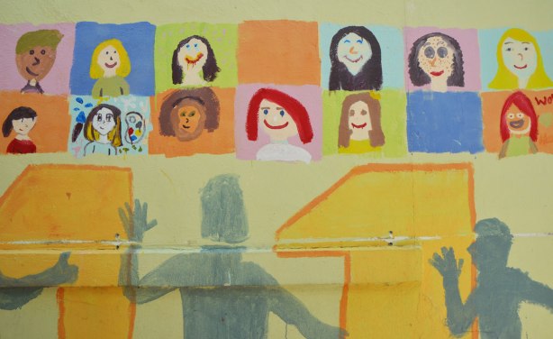 Part of a mural in an alley painted by students from Gledhill Public school, graduating class of 2011. 2011 in large numbers across the bottom with grey silhouettes of people, brightly coloured squares with faces across the top