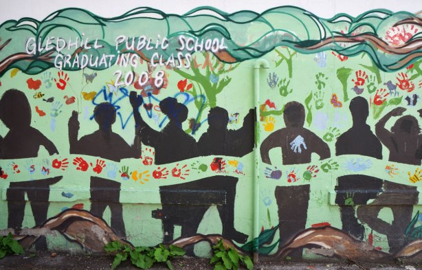 Part of a mural in an alley painted by students from Gledhill Public school, graduating class of 2008, black silhouettes under tree branches, hand prints too