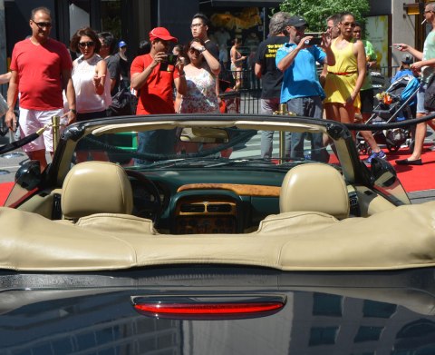 dark green convertible in the foreground, people looking at in the background
