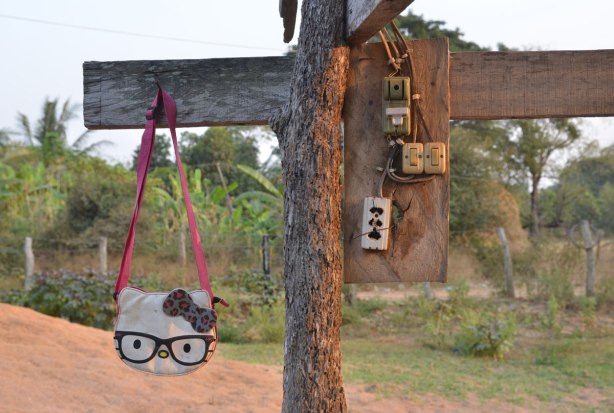 A hello Kitty purse hangs from a piece of wood beside 4 small electrical boxes with switches and outlets