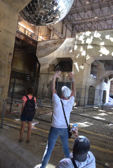 one man is taking another man's picture from an angle that it makes it look like the second one is holding up a giant disco ball, reflecting globe with 1000 mirrors on it, inside the Hearn generating station