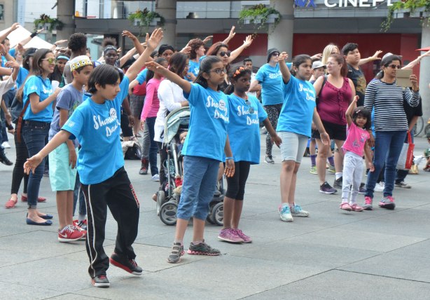 people dancing at Yonge Dundas Square as a group, part of an event called Sharing Dance - kids