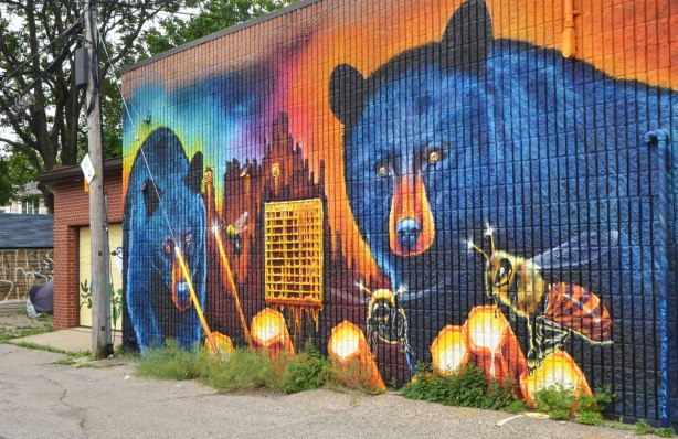 large mural by Nick Sweetman on a wall in Frank Kovac Lane, two very large blue bears are eating honey from honeycombs while a few large bees buzz around. 