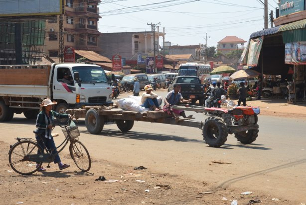 a couple drives a vehicle that is made of a truck chassis and four wheels, no body, through an intersection