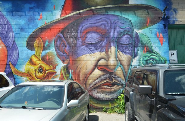 mural of a man's face, eyes closed, wearing a hat, mustache, older man
