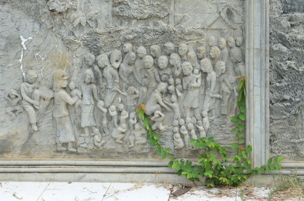 bas relief sculpture of children being taken from their parents during the Khmer Rouge regime, in stone, bottom part of a memorial stupa 