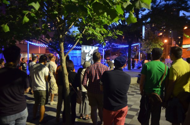 a group of people stand around a stage watching a dance performance